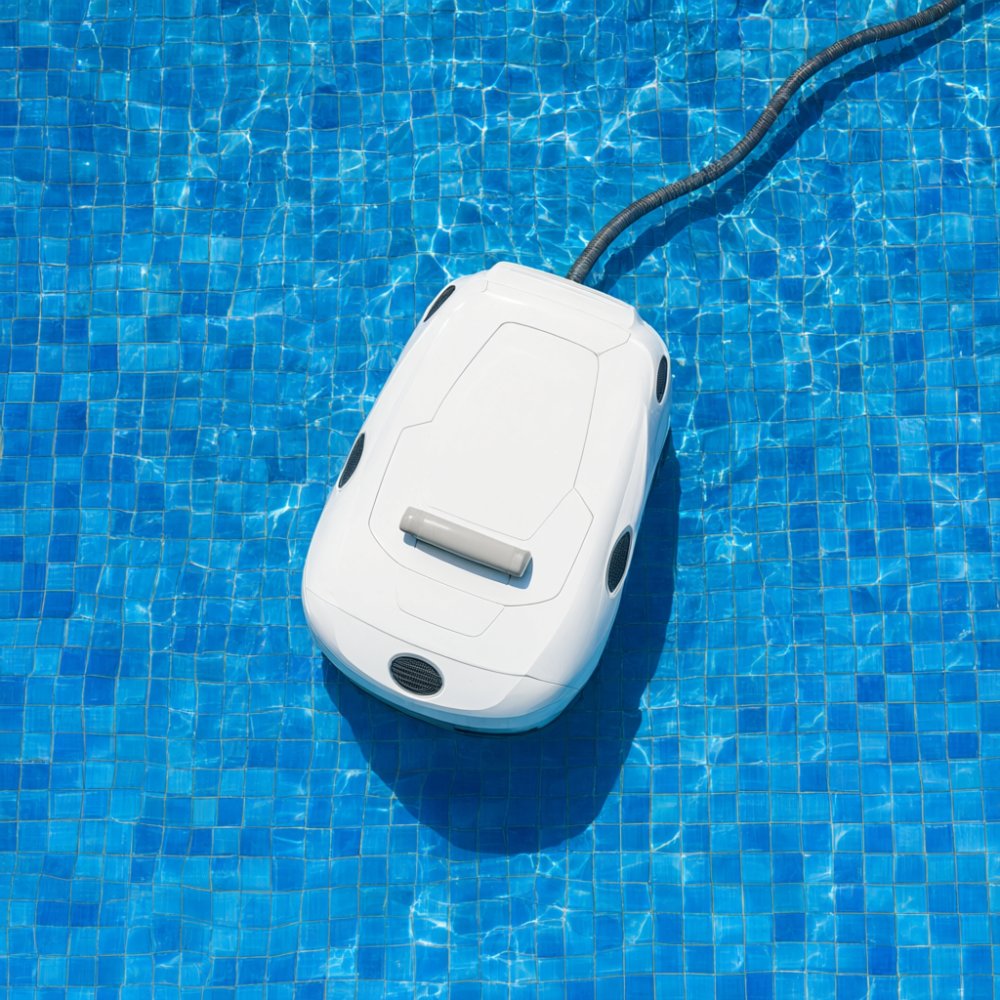 White robotic pool cleaner floating on blue mosaic pool tiles